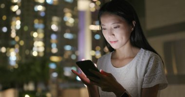 Genç kadın çalışma gece şehirde cep telefonu üzerinde