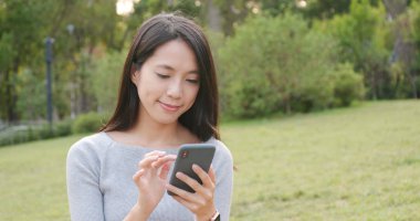 Parkta cep telefonu kullanan bir kadın.