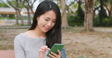 Parkta cep telefonu kullanan bir kadın.