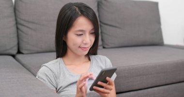 Kadın evde cep telefonu üzerinde okuma