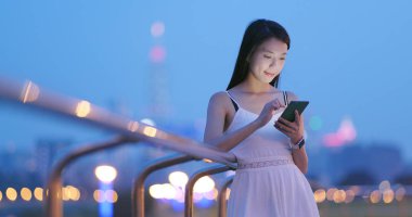 Genç kadın cep telefonuyla şehirde geceleri