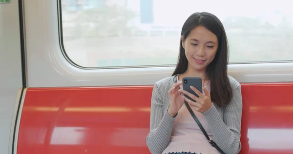 Woman using smartphone on train compartment