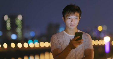 Geceleri cep telefonu kullanan adam.