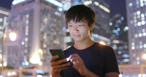 Man using mobile phone in city at night