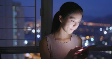 Evde akıllı telefon kullanan bir kadın.