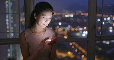 Evde cep telefonu kullanan Asyalı kadın.