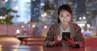 İş kadını gece şehirde smartphone bak