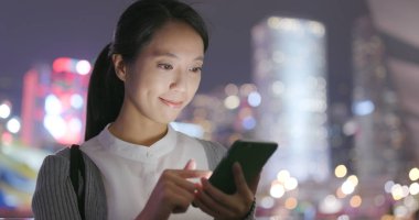 Geceleri cep telefonu kullanan genç bir kadın.