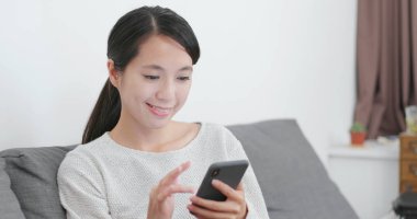 Evde cep telefonu kullanan bir kadın