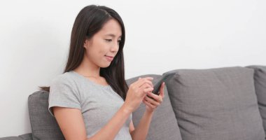 Evde akıllı telefon kullanan bir kadın.