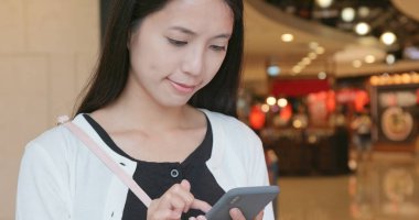 alışveriş merkezinde cep telefonu kullanan kadın