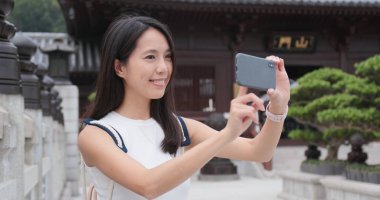 Çin bahçede telefon ve video çekmek için akıllı telefon kullanan kadın seyahat