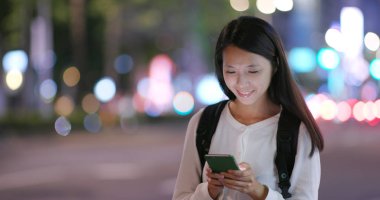 Smartphone şehirde geceleri kullanan kadın