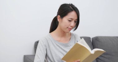 Kanepede kitap okuyan kadın.