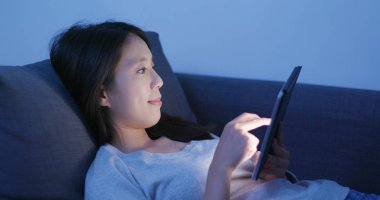 Dijital tablet bilgisayarda izlemek ve gece kanepede yatan kadın