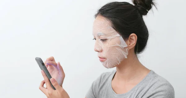 Donna Applicare Maschera Sul Viso Utilizzando Smartphone Casa — Foto Stock