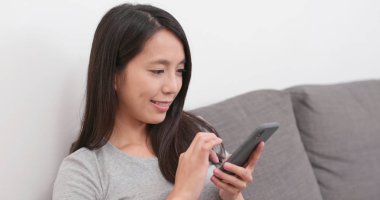 Evde cep telefonu kullanan bir kadın