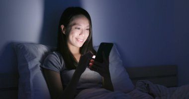 Geceleri cep telefonu kullanan bir kadın.