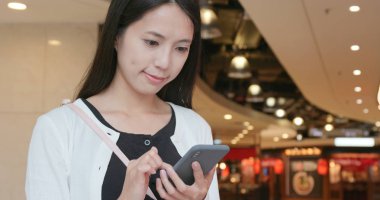 alışveriş merkezinde cep telefonu kullanan kadın