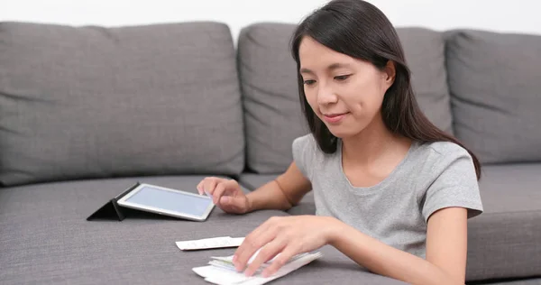 Woman record the daily expense of tablet computer at home