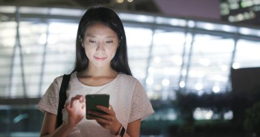 Smartphone tren istasyonunda gece kullanan kadın