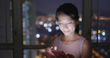 Evde cep telefonu kullanan Asyalı kadın.