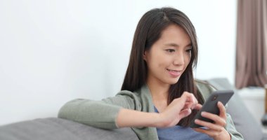 Evde cep telefonu kullanan bir kadın