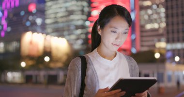 Tablet bilgisayar geceleri açık istasyonda kullanarak iş kadını