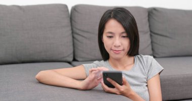 Evde cep telefonu kullanan bir kadın