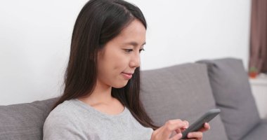 Evde akıllı telefon kullanan bir kadın.