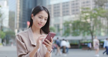 Cep telefonu açık, üzerinde çalışan genç kadın