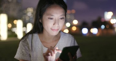 Cep telefonuyla Şehir Parkı içinde geceleri kadın