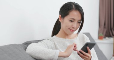 Evde cep telefonu kullanan bir kadın