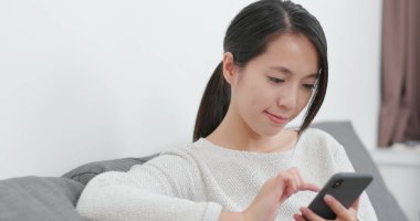 Evde cep telefonu kullanan bir kadın