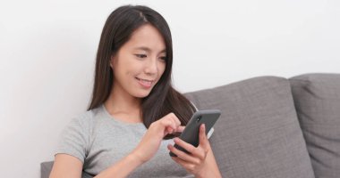 Evde akıllı telefon kullanan bir kadın.