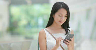 Alışveriş merkezinde indirim aramak için cep telefonu kullanan kadın