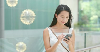 Alışveriş merkezinde indirim aramak için cep telefonu kullanan kadın