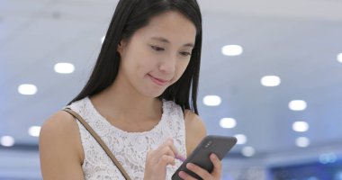 Genç kadın Alışveriş Merkezi'ndeki smartphone kullanarak