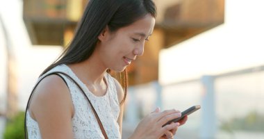 Günbatımı altında cep telefonu kullanan kadın