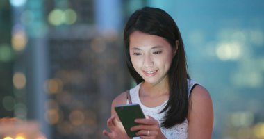 Geceleri cep telefonu kullanan bir kadın.