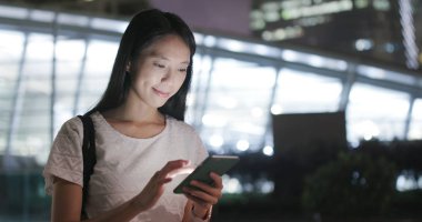 Smartphone tren istasyonunda gece kullanan kadın