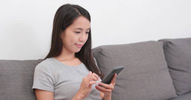 Evde cep telefonu kullanan bir kadın