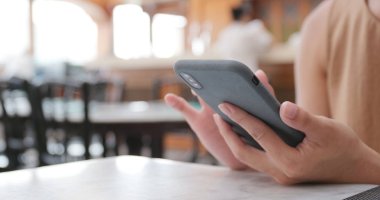 Kahve dükkanında cep telefonu kullanan kadın