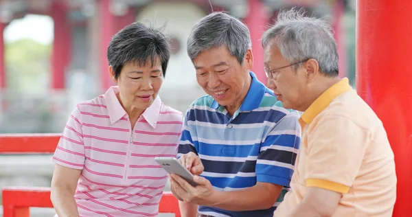 Elderly friends look at mobile phone together