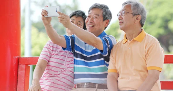 Üst düzey arkadaş birlikte konuşma ve açık Parkı'nda selfie ile cep telefonu al