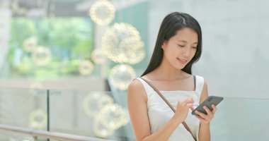 Alışveriş merkezinde indirim aramak için cep telefonu kullanan kadın