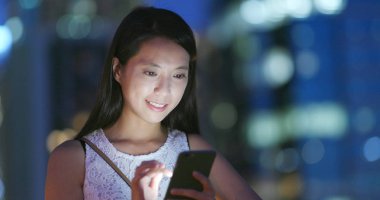 Geceleri cep telefonu kullanan bir kadın.