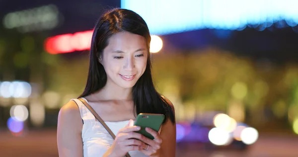 Asian Woman using app on cellphone in city at night