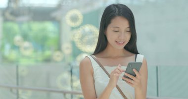 Alışveriş merkezinde indirim aramak için cep telefonu kullanan kadın