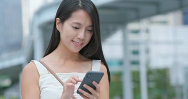 Şehirde cep telefonu kullanan genç bir kadın.